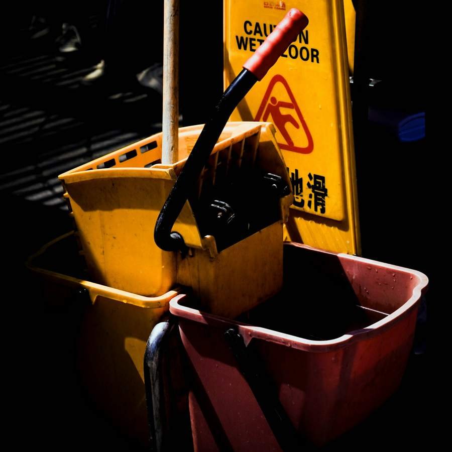Yellow mop bucket and wet floor sign for housekeeping